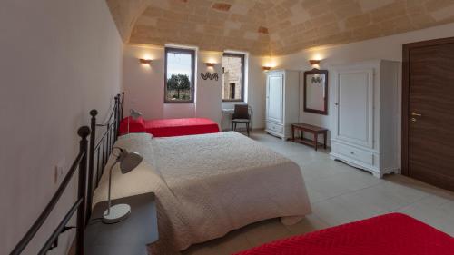 a bedroom with two beds with red sheets and a desk at Masseria Giustiniani in Torricella