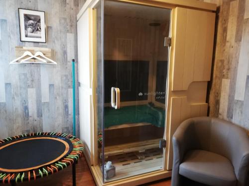 a glass shower door in a room with a chair at Celine'Home in Saint-Germain-sur-Morin