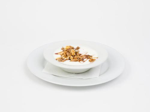 a bowl of yogurt with nuts on a white plate at Hotel Roma in Sarria