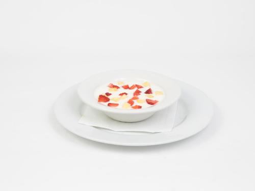 a bowl of cereal with strawberries on a plate at Hotel Roma in Sarria