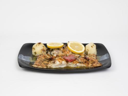 a plate of food with fish and potatoes and lemon slices at Hotel Roma in Sarria