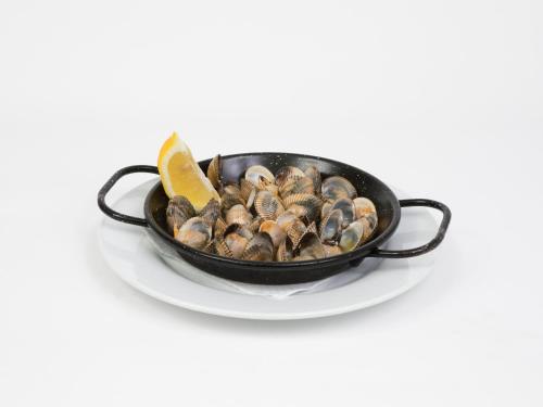 a pan of clams on a plate with a slice of lemon at Hotel Roma in Sarria
