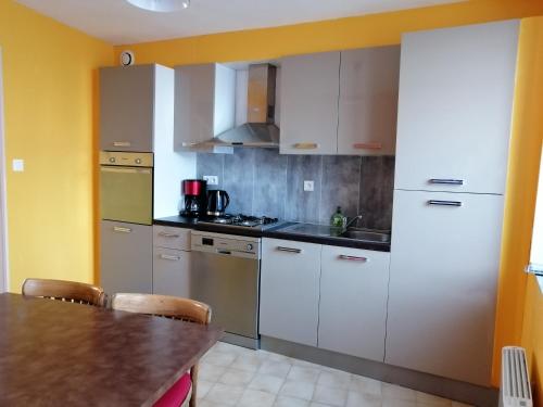a kitchen with stainless steel appliances and a table at Les orchidées in Picauville