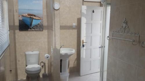 łazienka z toaletą, umywalką i drzwiami w obiekcie Casa Angelo w mieście Vanderbijlpark