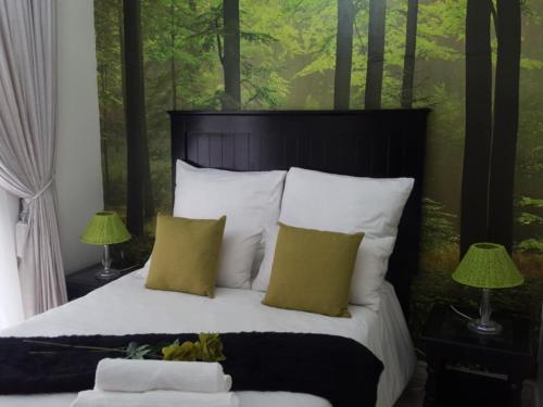 a bedroom with a bed with white pillows and green walls at Casa Angelo in Vanderbijlpark