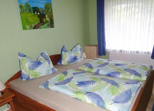 a bed with blue and white sheets and pillows at Haus Ramona in Struckum