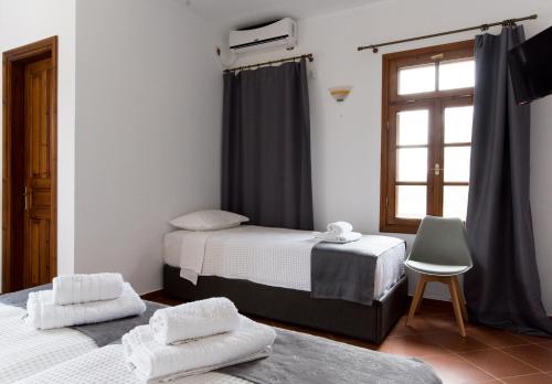 two beds in a room with a window and a chair at Platanorema in Agios Ioannis Prodromos