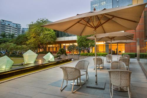 a patio with tables and chairs and an umbrella at Crowne Plaza Guangzhou Huadu, an IHG Hotel in Guangzhou