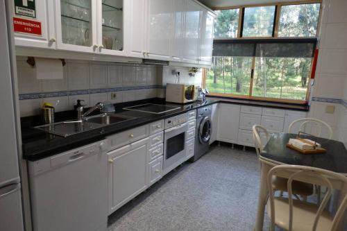 a kitchen with white cabinets and a sink and a dishwasher at AZURARA BEACH large and sunny apartment in Árvore