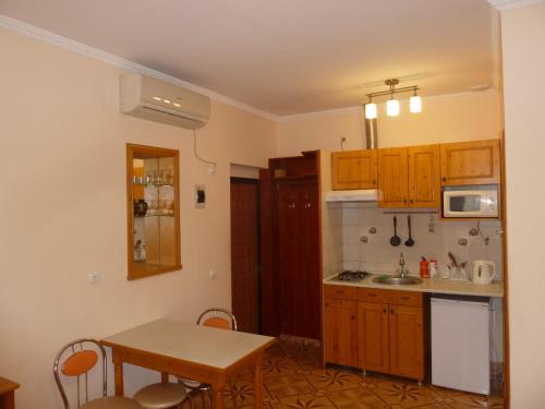 ソチにあるАпартаменты Sunnyのキッチン(木製キャビネット、テーブル、シンク付)