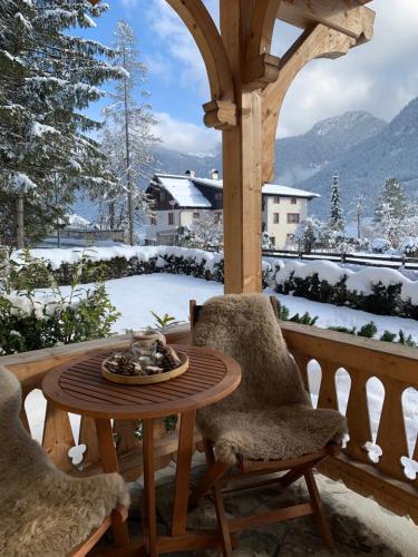 a table and two chairs on a porch with snow at Der Ulmenhof in Gosau