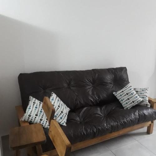 a black leather couch with pillows on it at Depto Temporario La Plata in La Plata