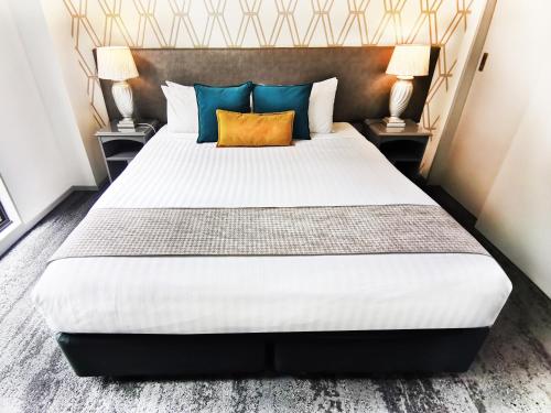 a bedroom with a large bed with two lamps at Quest on Eden Auckland CBD Apartment Hotel in Auckland