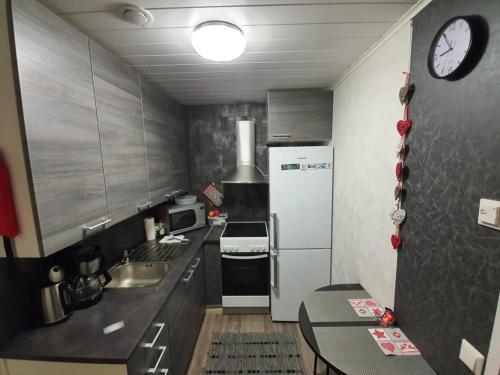 una cucina con frigorifero, tavolo e orologio di Apartment Neitamo44 a Ivalo