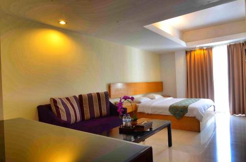 a hotel room with a bed and a couch at Sunset Residence and Condotel in Legian