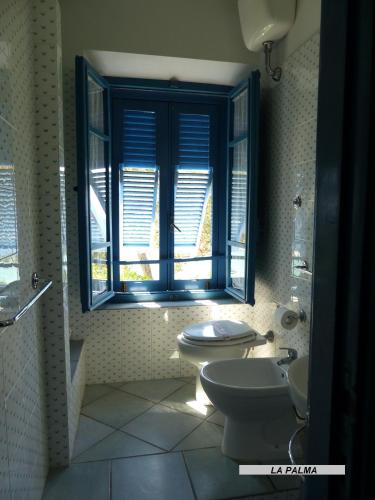 a bathroom with a toilet and a sink and a window at Appartamenti Villa Lina in Nisporto