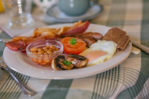 un piatto di alimenti con uova bacon pomodori e fagioli di Yew Tree Farm a Congleton