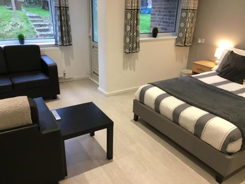 a bedroom with a bed and a chair and a table at Spacious ground floor studio flat - easy access to Stansted Airport, London and Cambridge in Bishops Stortford