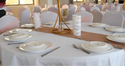 a table with white plates and utensils on it at Hôtel Résidence Madiba in Lomé
