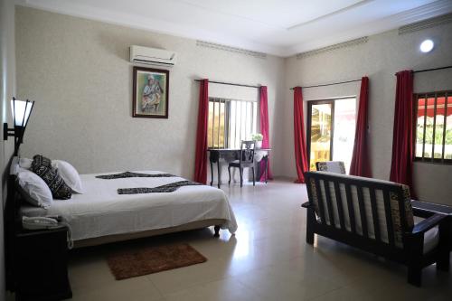 um quarto com uma cama, uma mesa e janelas em Hôtel Résidence Madiba em Lomé