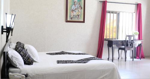 a bedroom with a bed and a table and a window at Hôtel Résidence Madiba in Lomé
