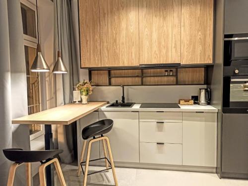 a kitchen with white cabinets and a wooden table and stools at Comfy Apartments - Old Town Center in Gdańsk
