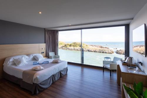a hotel room with a bed and a view of the ocean at Hotel Astuy in Isla