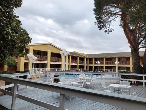 a resort with a pool and tables and chairs at Days Inn by Wyndham Lawton in Lawton