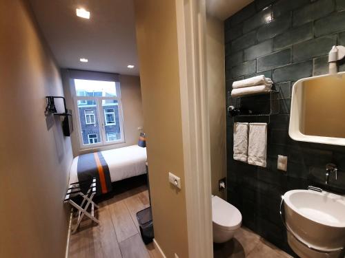 a bathroom with a toilet and a sink and a bed at RoomWest in Amsterdam