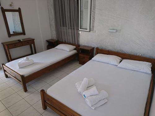 two beds in a hotel room with towels on them at Tilegrafos Studios in Lefkada