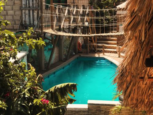 a swimming pool with a hammock in a garden at Hostal Kaia in Santa Marta