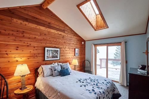 a bedroom with a wooden wall with a bed and a window at Heart of Superior Lake Cabin 15 Mi to Lutsen Mtn! in Schroeder