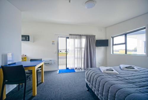 Habitación de hotel con cama, escritorio y mesa. en Hokitika's Kiwi Holiday Park and Motels en Hokitika