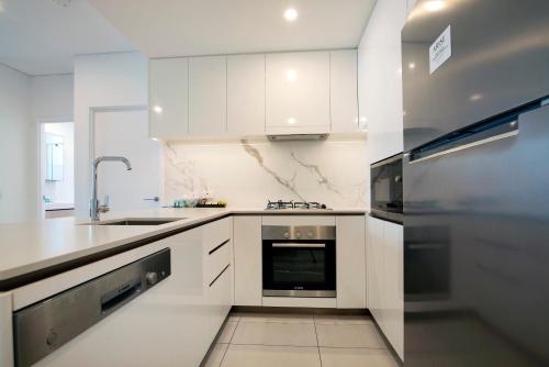 a white kitchen with a sink and a stove at Hope Street Apartments by CLLIX in Brisbane