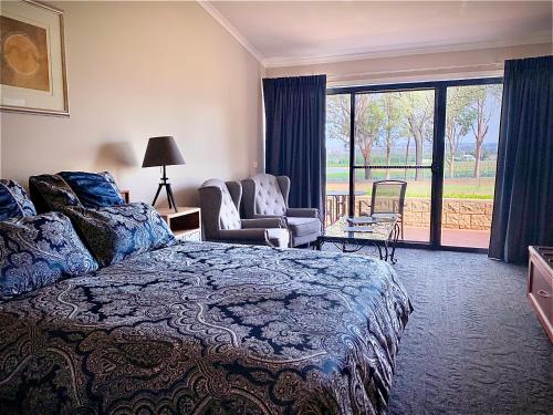 a bedroom with a bed and a chair and a window at Estate Tuscany in Pokolbin