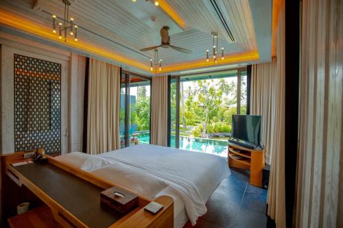 a bedroom with a bed and a television and a pool at Baba Beach Club Natai Luxury Pool Villa Hotel by Sri panwa - SHA Plus in Natai Beach