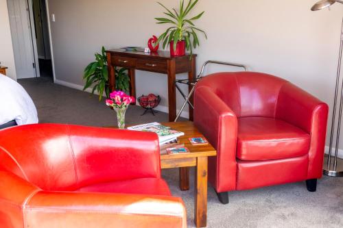 two red chairs and a table in a room at Ribbonwood Country House in Cheviot