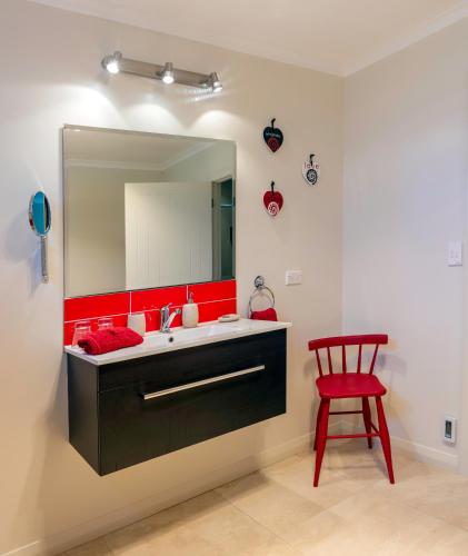 a bathroom with a sink and a red chair at Ribbonwood Country House in Cheviot