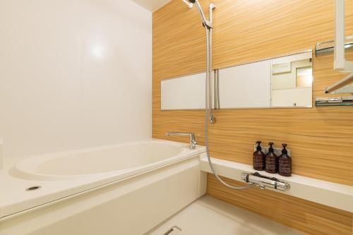 a bathroom with a bath tub and a sink at GRAND BASE Nagasaki City in Nagasaki