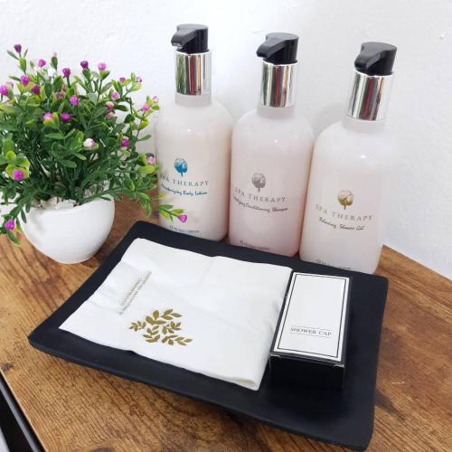 a table with three bottles of soap and a book at Oblique Apartment - ออฟบลิค อพาร์ทเมนท์ in Nonthaburi