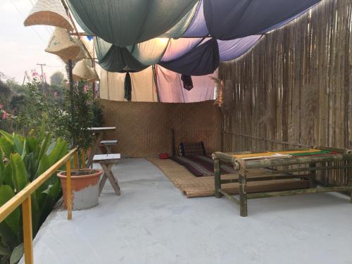a patio with an umbrella and a bench and plants at Thong Family Homestay Chiangdao in Chiang Dao