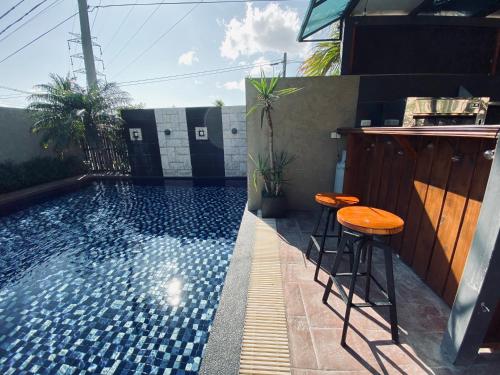 a swimming pool with stools next to a house at 墾丁裡小路包棟Villa in Nanwan