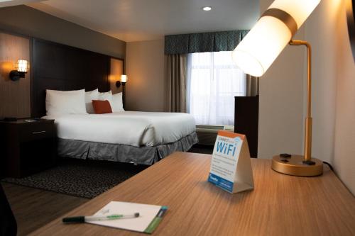 a hotel room with a bed and a desk with a lamp at Wingate by Wyndham - DFW North in Irving