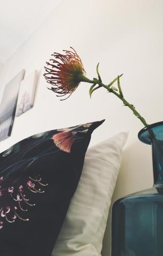 a flower on a pillow next to a blue vase at Nepean Shores by Gateway Lifestyle Holiday Parks in Penrith