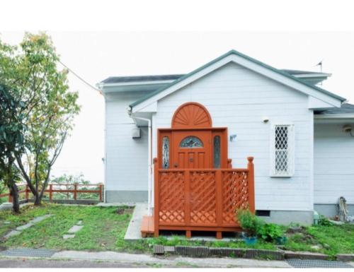 a small white house with a wooden gate at ANJIN Stay Awaji - Resort villa with ocean view & BBQ - Self Check-In Only in Akashi