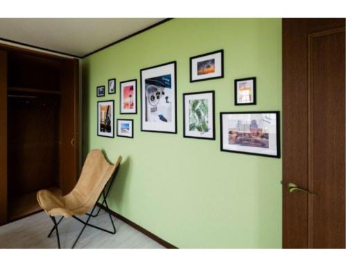 a room with a chair and pictures on a green wall at ANJIN Stay Awaji - Resort villa with ocean view & BBQ - Self Check-In Only in Akashi