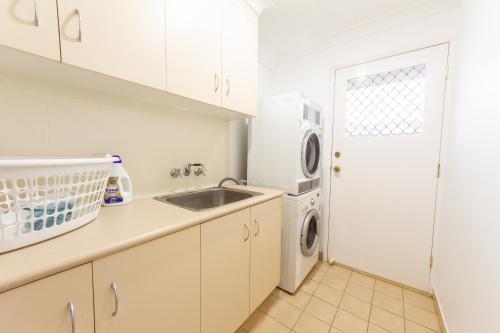 a white kitchen with a sink and a washing machine at Executive and Family Home Large - Flinders View 24 in Ipswich