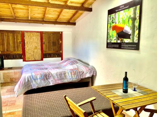 Un dormitorio con una cama y una mesa con una botella de vino en Compostela cabaña privada (private cabin for rent), en Jardín