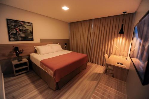 a bedroom with a bed and a table and a desk at Figueiras Hotel & Eventos in São Miguel dʼOeste