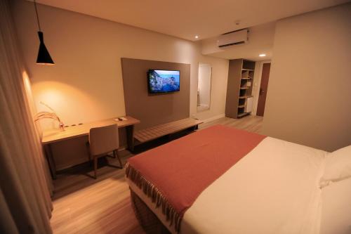 a bedroom with a bed and a desk and a television at Figueiras Hotel & Eventos in São Miguel dʼOeste